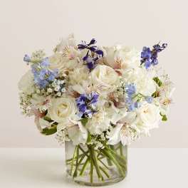 White and blue mixed bouquet in a clear glass vase