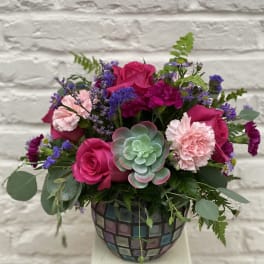 Pink roses and carnations in a mosaic vase with a succulent accent