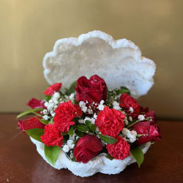 Red roses and carnations in a white shell-shaped basket