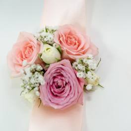 Pink rose wrist corsage with white filler flowers on a pale ribbon