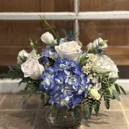 Blue hydrangeas and white roses arranged in a glass vase