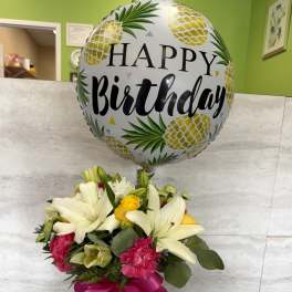 Birthday balloon above a mixed bouquet in a glass vase
