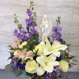 Purple and cream floral arrangement with a white angel figurine