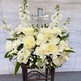 White floral arrangement with a silver cross centerpiece