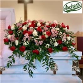Large red, white, and pink floral spray on a white casket