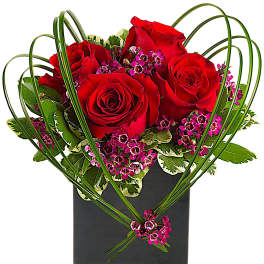 Red roses and pink filler flowers in a black square vase