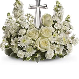 White floral arrangement with roses and a silver cross centerpiece