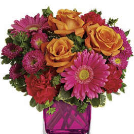 Pink and orange mixed bouquet in a square glass vase