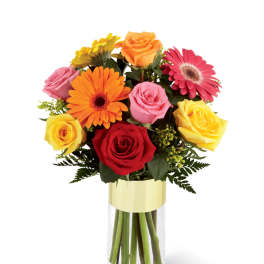Mixed bouquet of roses and gerbera daisies in a clear glass vase