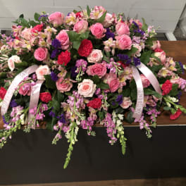 Large pink and purple floral casket spray with ribbon streamers