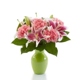 Pink lilies and carnations arranged in a light green vase
