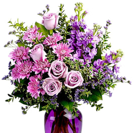 Pink and lavender flowers arranged in a purple glass vase