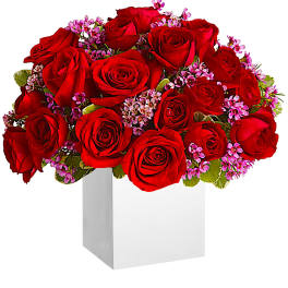 Red roses with pink filler flowers in a white box vase