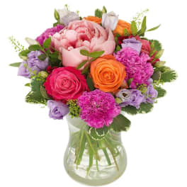Mixed bouquet of pink, orange, and lavender flowers in a glass vase