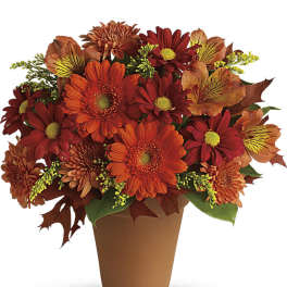 Orange and red mixed flower arrangement in a brown pot
