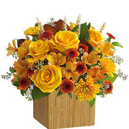 Yellow roses and orange mums arranged in a wooden box