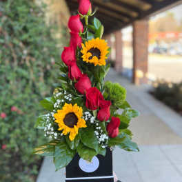 Tall arrangement of red roses and sunflowers in a black box