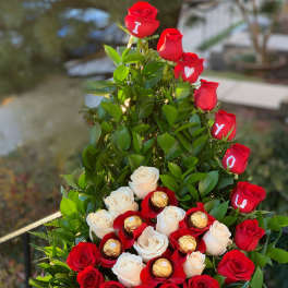 Basket arrangement of red and white roses with chocolates and letters