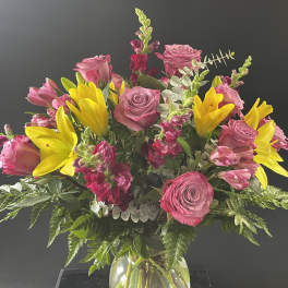 Pink roses and yellow lilies in a clear glass vase