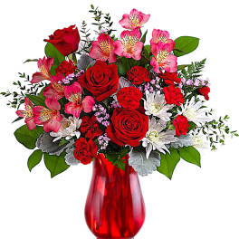 Red roses and pink alstroemeria in a red glass vase