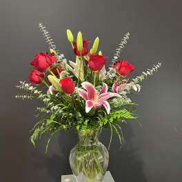 Red roses and pink lilies in a clear glass vase