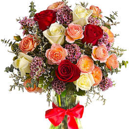 Bouquet of red, white, and peach roses in a glass vase with a red ribbon