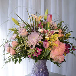 Mixed pink and yellow flowers arranged in a purple vase