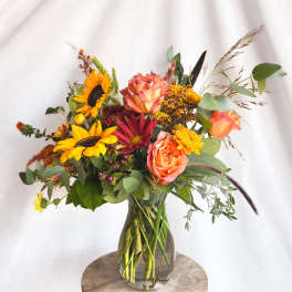 Mixed bouquet in a clear glass vase with sunflowers and peach roses