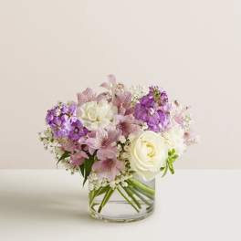 Bouquet of white roses and pink-purple flowers in a clear glass vase