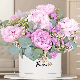 Pink peonies and small white flowers in a white hatbox