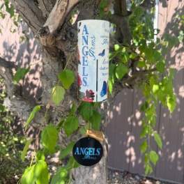 Memorial wind chime with angel-themed text and butterflies hanging from a tree branch