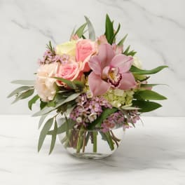 Pink and cream floral bouquet in a clear glass vase