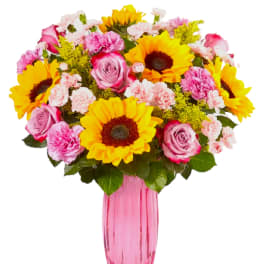 Bouquet of sunflowers, pink roses, and carnations in a pink vase