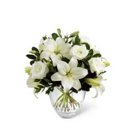 White lilies and roses arranged in a clear glass vase