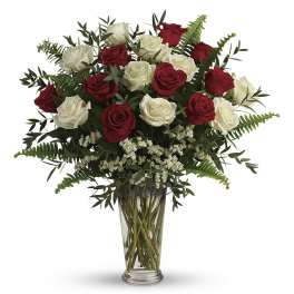 Red and white roses arranged in a clear glass vase