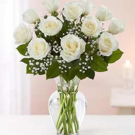 White roses arranged in a clear glass vase with baby's breath