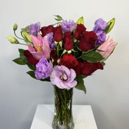Bouquet of red roses and pink lilies in a clear glass vase
