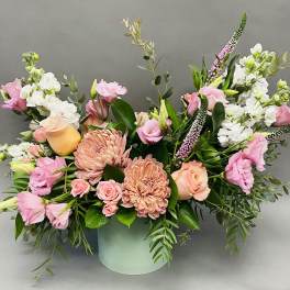 Pink and peach flowers arranged in a pale green vase
