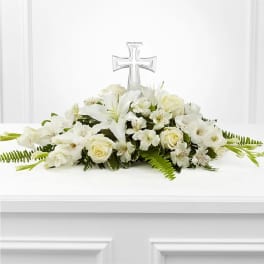 White floral casket spray with a clear cross centerpiece
