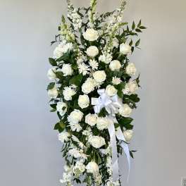 White floral standing spray with roses and ribbon on an easel