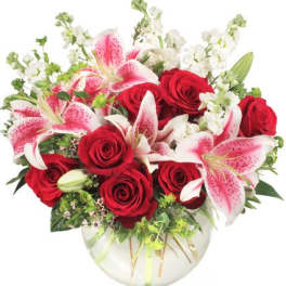 Bouquet of red roses and pink lilies in a clear glass vase