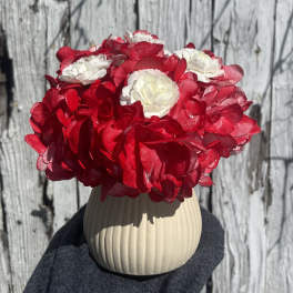 Red and white flower arrangement in a beige ribbed vase