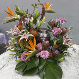 Tropical floral centerpiece with pink roses and lilies around a silver urn