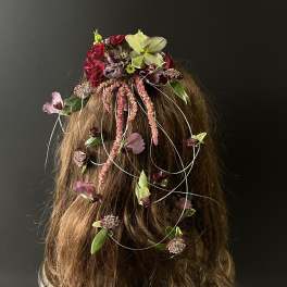 Floral hairpiece with red, pink, and green blooms on long hair