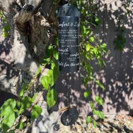 Black memorial wind chime hanging from a tree