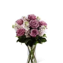 Lavender roses and soft white stock arranged in a clear glass vase