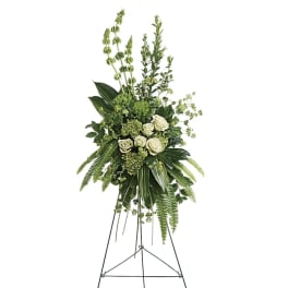 Tall green and white standing floral spray with roses and greenery on a black metal easel