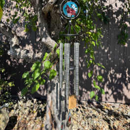 Wind chime hanging from a tree branch with a small bird ornament