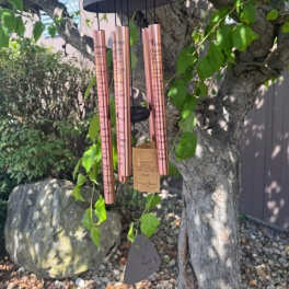 Copper wind chime hanging from a tree branch
