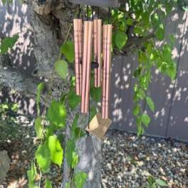 Rose-gold wind chime hanging from a tree branch